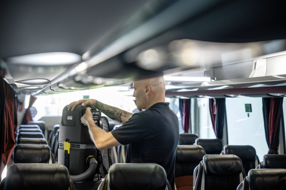 Mann reinigt das Innere eines Reisebusses mit einem Kärcher Rucksackstaubsauger